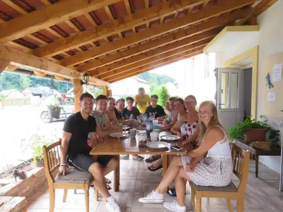 a group of people sitting around a wooden table at Mill House Apartment and Camping in Ljutomer