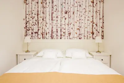 a bedroom with a white bed with two lamps at WH Apartments in Ljubljana