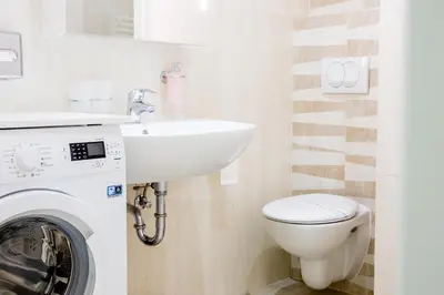 a bathroom with a sink and a washing machine at WH Apartments in Ljubljana
