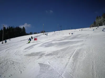a group of people skiing down a snow covered slope at APARTMENTS ROGLA JURGOVO - Ski in Ski out in Lukanja