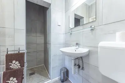 a white bathroom with a sink and a toilet at APARTMENTS ROGLA JURGOVO - Ski in Ski out in Lukanja