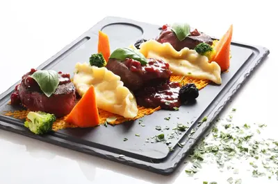 a black plate of food with vegetables and fruit at Hiša Pr'Pristavc in Bohinj