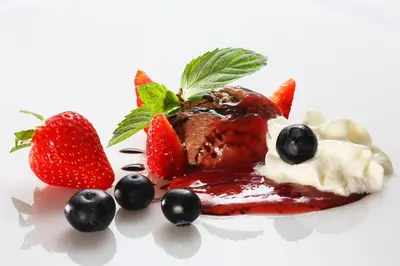 a dessert with strawberries and blueberries on a plate at Hiša Pr'Pristavc in Bohinj