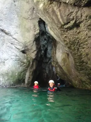 two people in the water in front of a cave at Hiša Pr'Pristavc in Bohinj