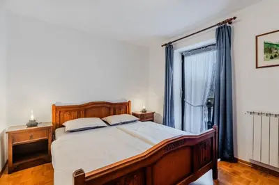 a bedroom with a wooden bed and a window at Apartments Mija in Krotica