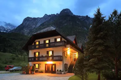 a large house in front of a mountain at Apartments Mija in Krotica