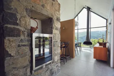 a living room with a stone wall with a tv at Vila Mravljevi Weinderer in Preserje