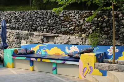 a colorful bench in front of a stone wall at Apartment Dandelion in Branik