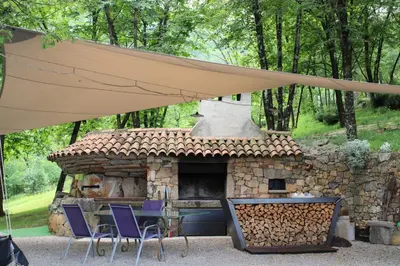 a table and chairs under a tent with a stone oven at Apartment Dandelion in Branik