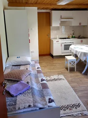 a room with two beds and a kitchen with a table at Dobra Hiša Zdravja Čičarija in Golac