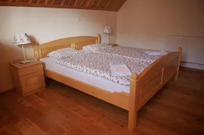 a bedroom with a wooden bed with a lamp and a dresser at Guesthouse Planinski Dom Majerhold in Solčava