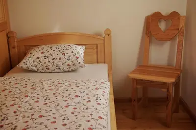 a bed with a pillow and a chair in a room at Guesthouse Planinski Dom Majerhold in Solčava