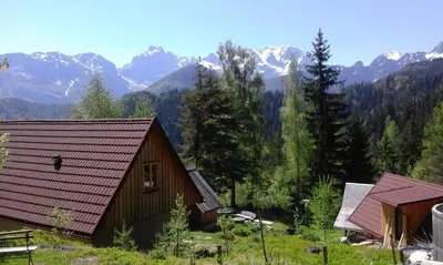 a couple of buildings with mountains in the background at Guesthouse Planinski Dom Majerhold in Solčava