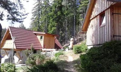 a couple of buildings with trees in the background at Guesthouse Planinski Dom Majerhold in Solčava