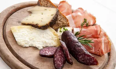 a plate of food with meats cheese and bread at Guesthouse Planinski Dom Majerhold in Solčava
