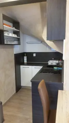 a kitchen with white cabinets and a black counter top at Apartment Borovnica in Moravske Toplice