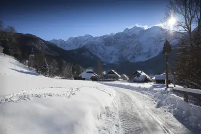 a road covered in snow with mountains in the background at Chalet Romantic in Zgornje Jezersko