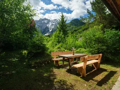 a picnic table with a bench and a view of a mountain at Chalet Romantic in Zgornje Jezersko