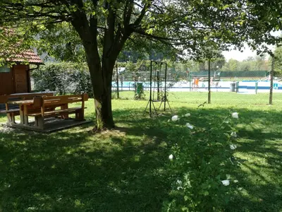 a park with a bench under a tree and a playground at Počitniška hiška Pod Skalco in Kamnik