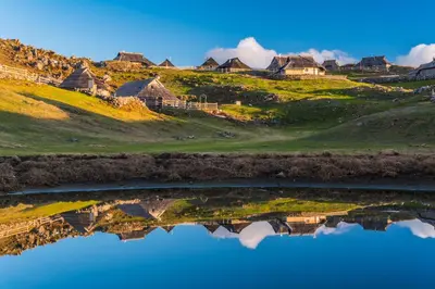 a reflection of houses on a hill in the water at Počitniška hiška Pod Skalco in Kamnik