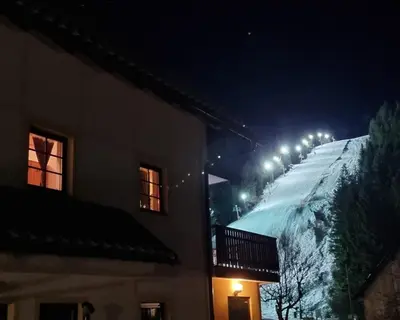 a row of lights on a snowy hill at night at Apartmaji Koželj in Ribnica na Pohorju