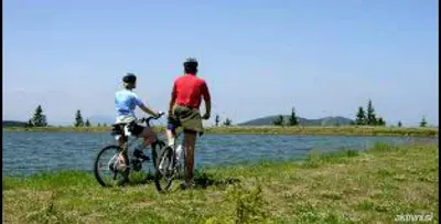 two men standing next to a bike next to a body of water at Apartmaji Koželj in Ribnica na Pohorju