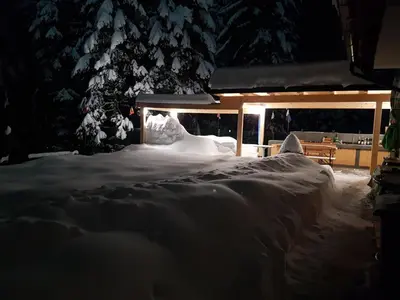a house covered in snow at night at Apartmaji Koželj in Ribnica na Pohorju