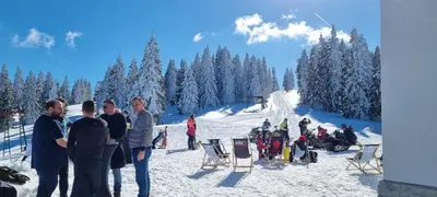 a group of people standing in the snow on a ski slope at Apartmaji Koželj in Ribnica na Pohorju