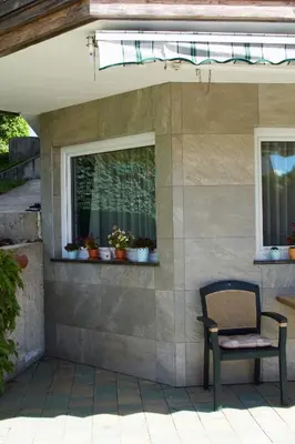 a chair sitting on a patio with two windows at Rudi Hiti's Guest House in Bled