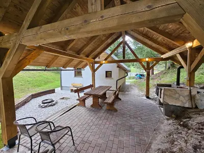 a wooden pavilion with a picnic table and benches at Lodge In Koprivnik in Koprivnik v Bohinju