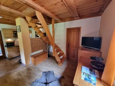a living room with a staircase and a television at Lodge In Koprivnik in Koprivnik v Bohinju