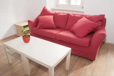 a red couch in a living room with a white table at Apartment Bon Voyage in Maribor