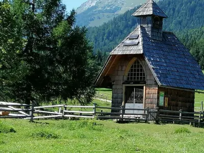 a small wooden building in a field next to a fence at Haus Alexandra Apartment in Bled