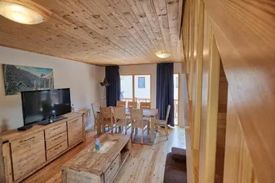 a living room with a television and a dining room at Jacobs Resort House Kranjska Gora in Kranjska Gora