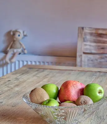 a bowl of apples and kiwis on a table at Jacobs Resort House Kranjska Gora in Kranjska Gora
