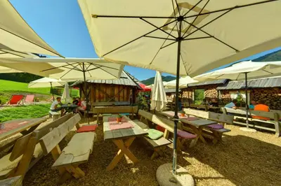a group of tables with umbrellas and people sitting around them at Jacobs Resort House Kranjska Gora in Kranjska Gora