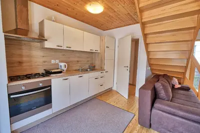 a kitchen with white cabinets and a couch in a room at Jacobs Resort House Kranjska Gora in Kranjska Gora