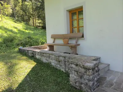 a bench sitting on a stone wall next to a window at House Dolenja Trebuša in Dolenja Trebuša