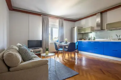 a living room with a couch and a kitchen with blue cabinets at Vila Tivoli in Ljubljana