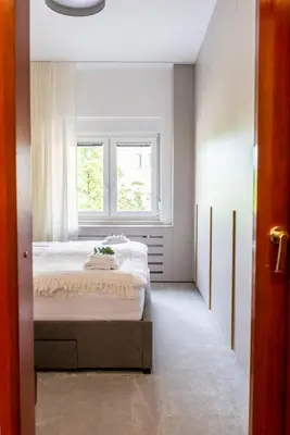 a white bedroom with a bed and a window at Vila Tivoli in Ljubljana