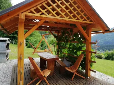 a wooden gazebo with a table and chairs on a deck at Počitniška hiška Kašta in Luče
