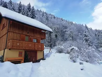 a building covered in snow with trees in the background at Počitniška hiška Kašta in Luče