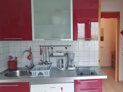 a kitchen with red cabinets and a sink at Apartments Tatjana in Bovec