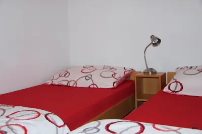 two beds with red and white sheets and a lamp at Apartments Tatjana in Bovec