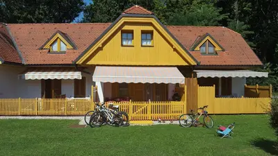 a yellow house with two bikes parked in front of it at Soncnica Apartment in Moravske Toplice