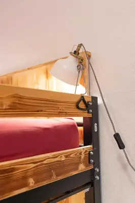 a lamp attached to a wall next to a bed at Turn Hostel in Ljubljana
