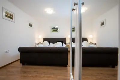 a bedroom with two beds and a black couch at Apartments Grom in Bled