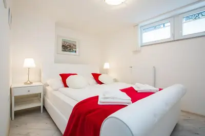a white bedroom with a bed with a red blanket at Apartments Grom in Bled