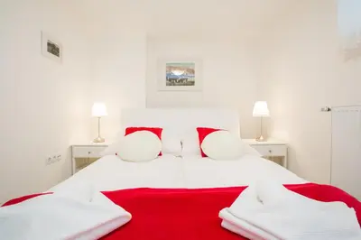 a white bed with red and white towels on it at Apartments Grom in Bled