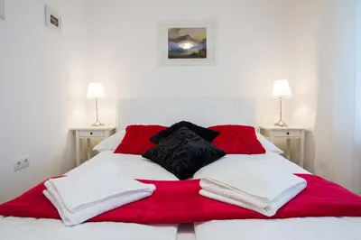 a bed with red and white blankets and pillows on it at Apartments Grom in Bled
